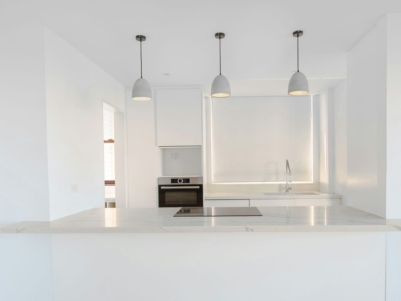 A bright white kitchen with pendant lights.